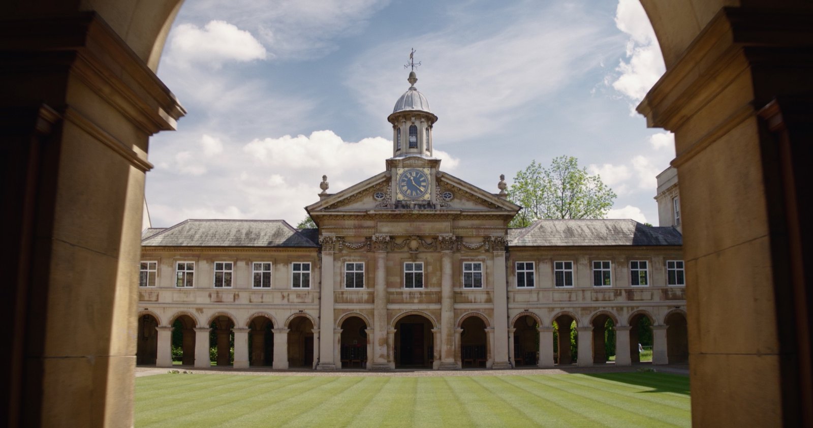 The front court and Wren chapel of Emmanuel College, Cambridge, seen through a stone archway
